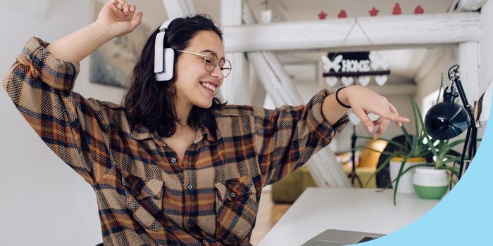 person with headphones sitting at a desk with a laptop dancing