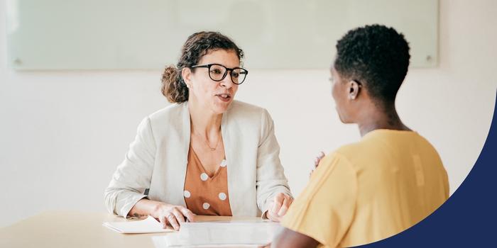 two people speaking during a job interview—the interviewer facing the camera and the interviewee facing away