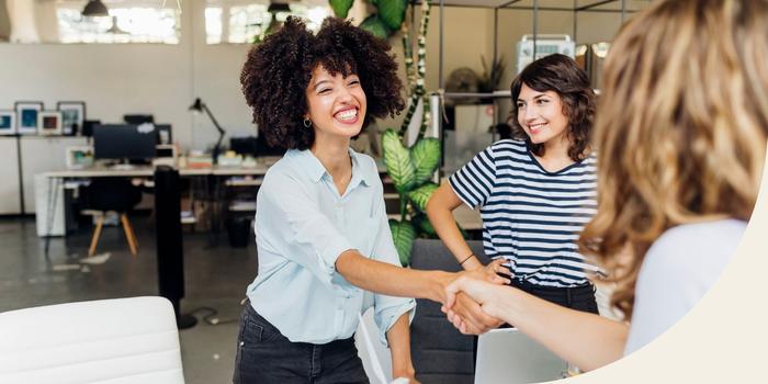 two people shaking hands in an open office before a job interview with a third person standing next to them