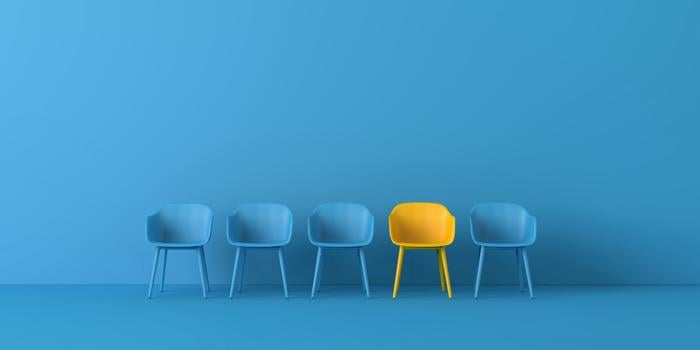 three empty blue chairs, one yellow empty chair, and another blue chair empty in a row against a blue wall on a blue floor