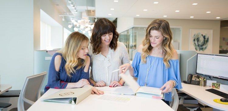 three Kendra Scott employees browsing through project notes