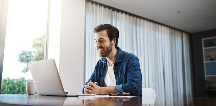 person smiling at computer and wearing headphones