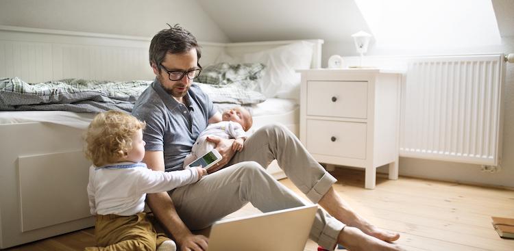 parent with toddler and baby working on laptop