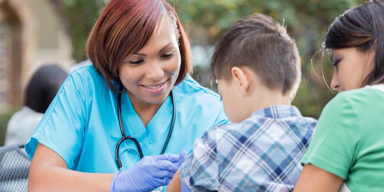 person in scrubs with stethoscope examining child outdoors