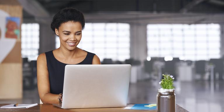 smiling person sitting and working on laptop in office