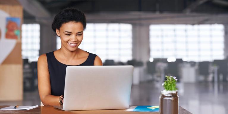 smiling person sitting and working on laptop in office