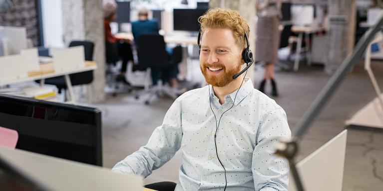 person sitting at desk in office with phone headset on