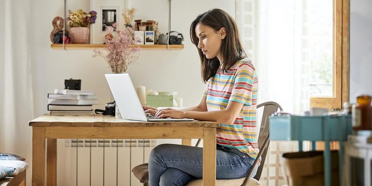 person sitting at table typing on a laptop
