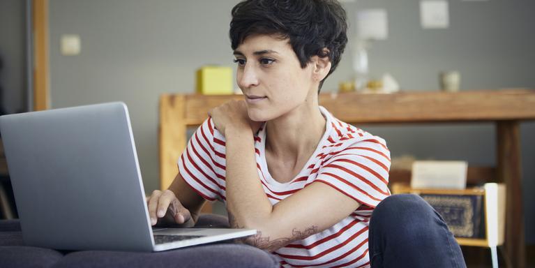 person sitting on floor using laptop on couch