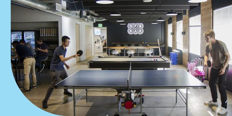 Employees playing ping pong in an office.