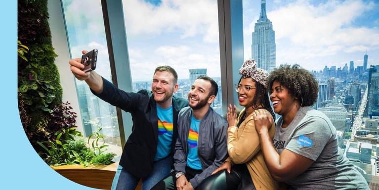 Salesforce employees taking a selfie by an office window overlooking the Empire State Building.