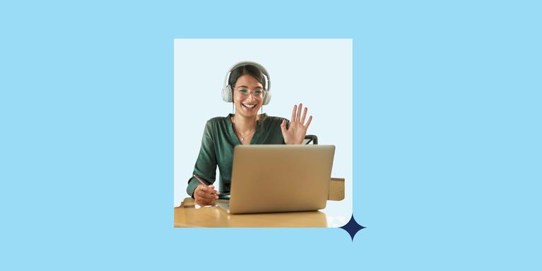 person sitting at a table wearing over-ear headphones, looking at an open laptop screen and raising one hand as if saying hello on a video call (all set in a light box with a navy blue star in the corner against a blue background)