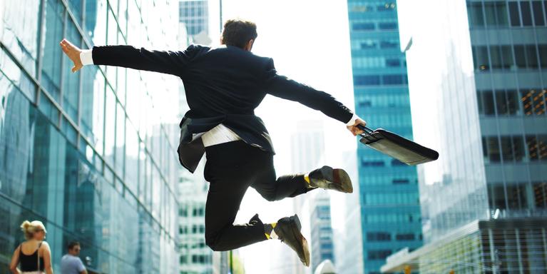 person in business suit jumping for joy on city street after successful interview