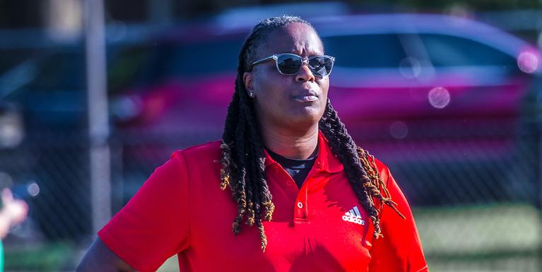 person with braids and sunglasses wearing a red polo shirt