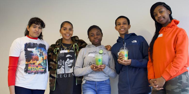 a group of teenagers pose with smoothies they made during a wellness workshop