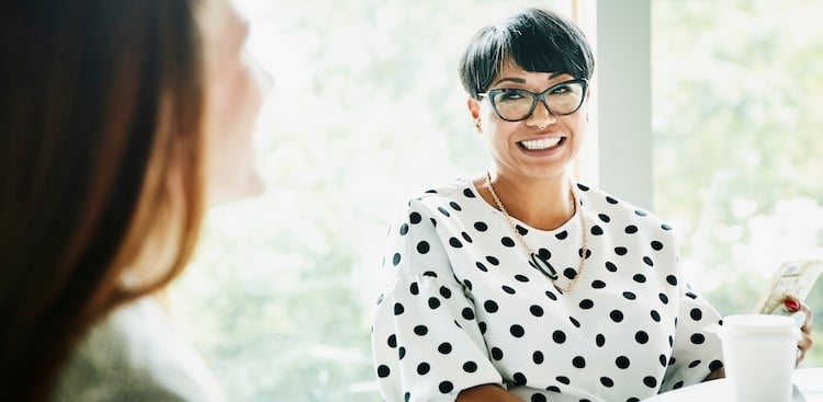 person with glasses and coffee smiling at boss