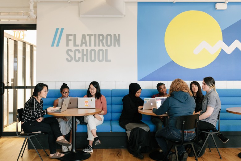 students with laptops sitting at tables in a Flatiron School cafe