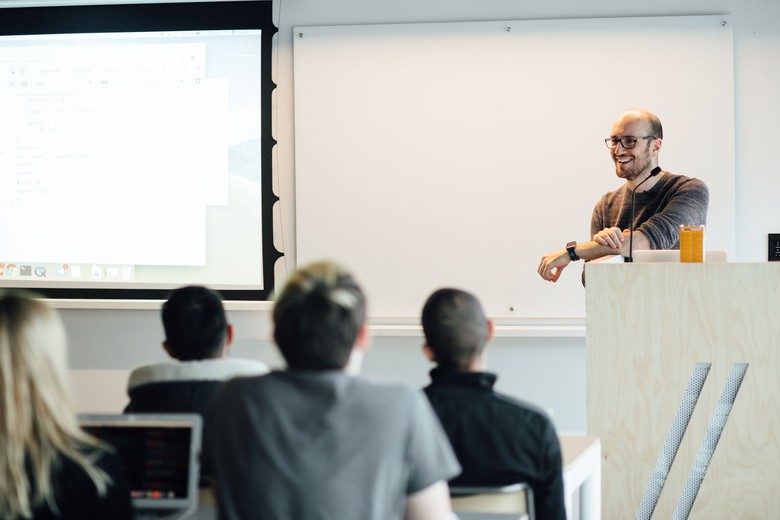 instructor standing at a podium at the front of a classroom
