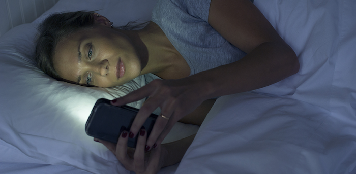 person looking at smartphone in bed
