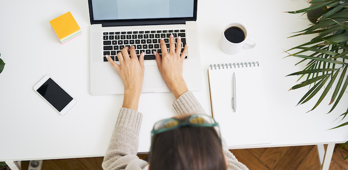 person sitting at a desk typing on a laptop