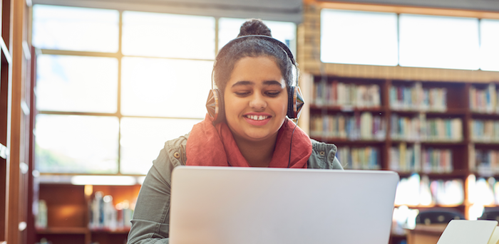 college student wearing headphones and working in the library