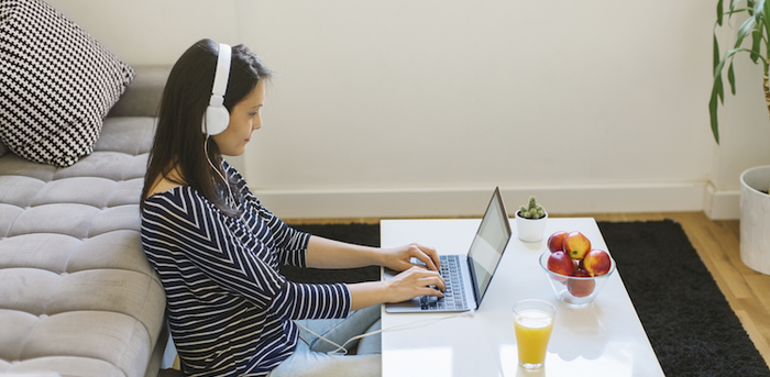 person sitting at a coffee table working on a laptop and wearing headphones