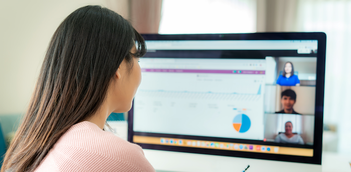 person sitting in front of a computer screen while on a video conference meeting with coworkers