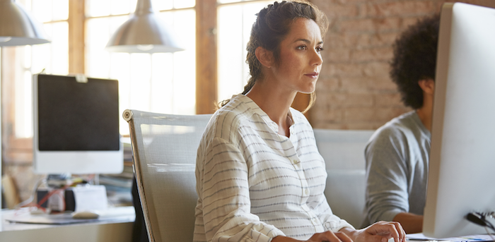 pregnant person sitting in front of a computer in an office