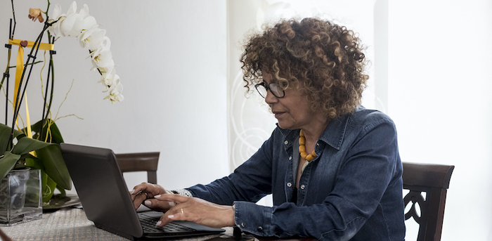 person sitting at a table at home working on a laptop