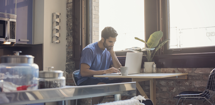 person sitting in the kitchen working on a laptop