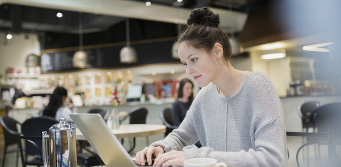 person sitting at a coffee shop working on a laptop