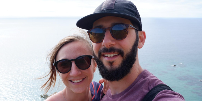 two people pose for a selfie with a body of water in the background