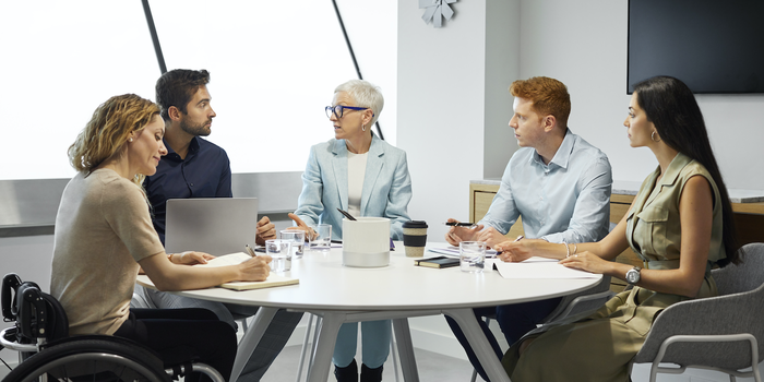 group of colleagues sitting around a table at the office having a discussion