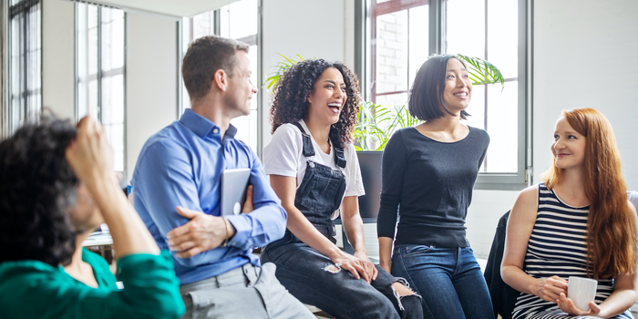 group of colleagues talking and laughing at the office