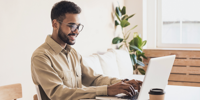 person sitting and working on a laptop with a cup of coffee nearby