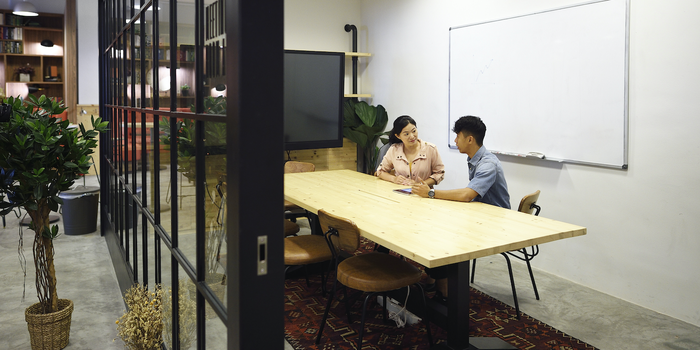 two people sitting at a table in a conference room at work talking