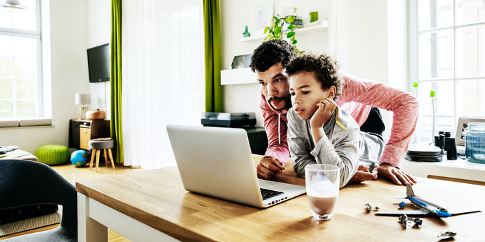 parent and child looking at a laptop screen together at home