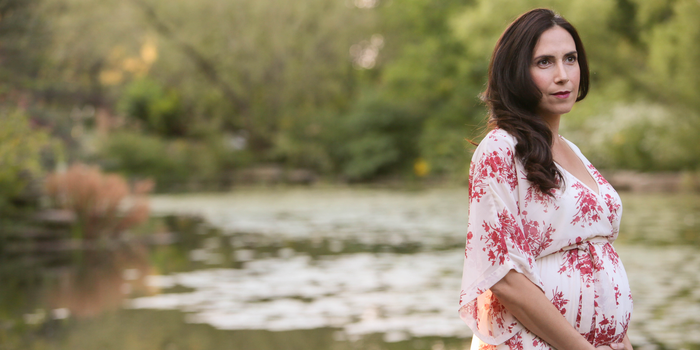 a photo of author Soraya Fata captured while she was pregnant with her daughter, with trees and a body of water blurred in the background