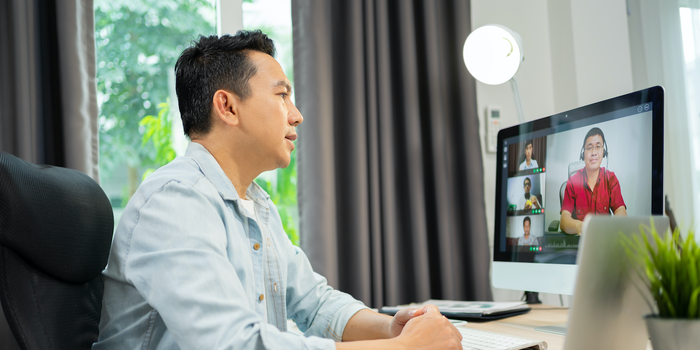 manager sitting at their desk speaking to their team on a video call