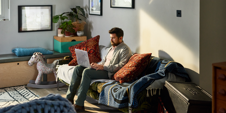 person sitting on couch at home typing on laptop