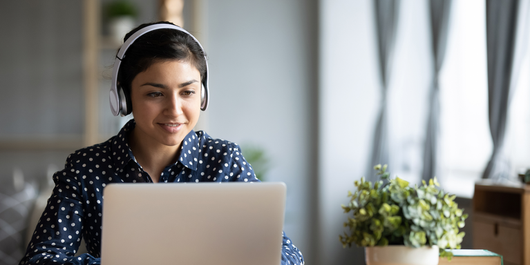 young adult sitting in front of a laptop wearing headphones