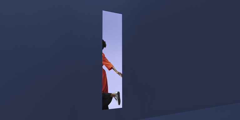 person stepping out of rectangular opening in colored wall