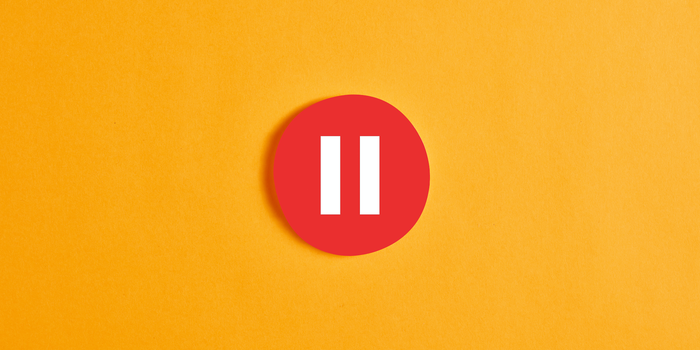 red and white circular pause button against an orange-yellow background